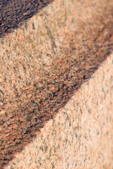 The texture of the figured processed surface of a large granite stone. Selective focus. Close-up.