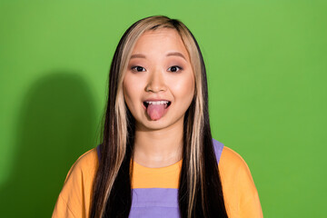 Photo portrait of attractive young woman stick tongue out dressed stylish violet yellow clothes isolated on green color background