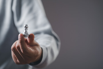 Businessman hand holding pawn chess for business strategy and leadership assignment concept.	
