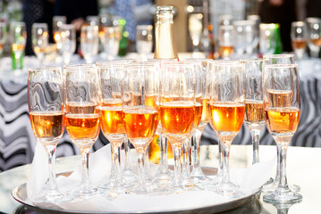 beautifully displayed glasses of sparkling wine and champagne with highlights on a tray at a festive event against the backdrop of bokeh of festive lights
