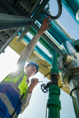 Industrial engineer adjusting pipeline valve with radio communication on construction site....