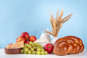 Happy Shavuot holiday background with summer red apples, wheat, grapes, dairy products - cheese,...