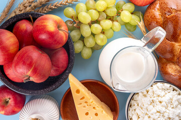 Happy Shavuot holiday background with summer red apples, wheat, grapes, dairy products - cheese, cottage cheese, milk or cream, copy space for text
