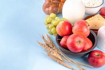 Happy Shavuot holiday background with summer red apples, wheat, grapes, dairy products - cheese, cottage cheese, milk or cream, copy space for text