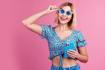 Photo of adorable pretty girl dressed blue top dark eyewear texting modern gadget empty space isolated pink color background