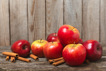 Apples with cinnamon on a textured wooden background. Fragrant red spiced apples with cinnamon sticks and star anise. Apple slices with spicy spices. Place for text. Copy space. Harvesting. Fruits. 