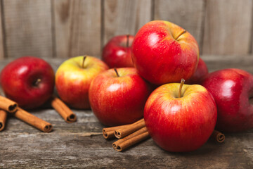 Apples with cinnamon on a textured wooden background. Fragrant red spiced apples with cinnamon sticks and star anise. Apple slices with spicy spices. Place for text. Copy space. Harvesting. Fruits. 