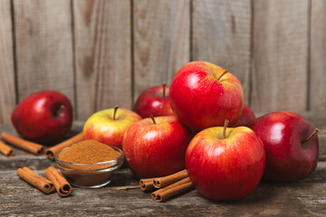 Apples with cinnamon on a textured wooden background. Fragrant red spiced apples with cinnamon sticks and star anise. Apple slices with spicy spices. Place for text. Copy space. Harvesting. Fruits. 