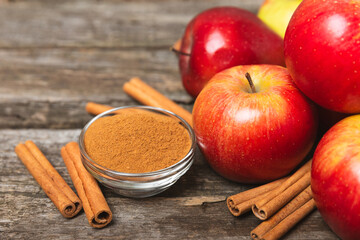 Apples with cinnamon on a textured wooden background. Fragrant red spiced apples with cinnamon sticks and star anise. Apple slices with spicy spices. Place for text. Copy space. Harvesting. Fruits. 