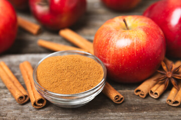 Apples with cinnamon on a textured wooden background. Fragrant red spiced apples with cinnamon sticks and star anise. Apple slices with spicy spices. Place for text. Copy space. Harvesting. Fruits. 