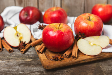 Apples with cinnamon on a textured wooden background. Fragrant red spiced apples with cinnamon sticks and star anise. Apple slices with spicy spices. Place for text. Copy space. Harvesting. Fruits. 