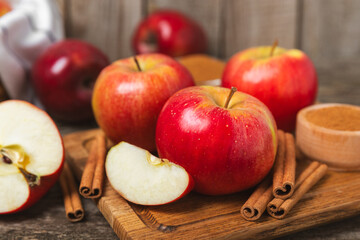 Apples with cinnamon on a textured wooden background. Fragrant red spiced apples with cinnamon sticks and star anise. Apple slices with spicy spices. Place for text. Copy space. Harvesting. Fruits. 