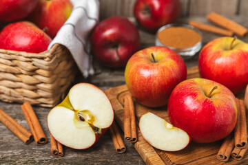 Apples with cinnamon on a textured wooden background. Fragrant red spiced apples with cinnamon sticks and star anise. Apple slices with spicy spices. Place for text. Copy space. Harvesting. Fruits. 