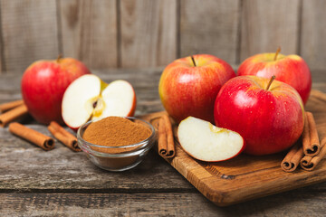 Apples with cinnamon on a textured wooden background. Fragrant red spiced apples with cinnamon sticks and star anise. Apple slices with spicy spices. Place for text. Copy space. Harvesting. Fruits. 