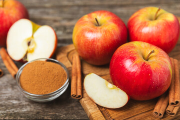Apples with cinnamon on a textured wooden background. Fragrant red spiced apples with cinnamon sticks and star anise. Apple slices with spicy spices. Place for text. Copy space. Harvesting. Fruits. 