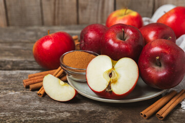 Apples with cinnamon on a textured wooden background. Fragrant red spiced apples with cinnamon sticks and star anise. Apple slices with spicy spices. Place for text. Copy space. Harvesting. Fruits. 