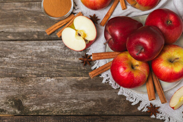 Apples with cinnamon on a textured wooden background. Fragrant red spiced apples with cinnamon sticks and star anise. Apple slices with spicy spices. Place for text. Copy space. Harvesting. Fruits. 