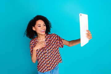 Portrait of optimistic funky girl wear print shirt look at tablet talk on video call palm on chest...