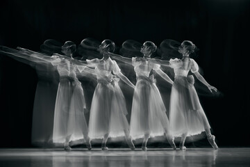 Black and white. Photo of artistic ballet dancers in mid-movement, their white tutus blending into...