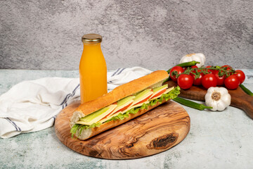 Cheddar sandwich on wood serving board. Sandwich made with tomatoes, cucumber, greens, cheddar cheese and special sauce