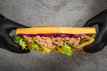 Tuna sandwich made with tuna meat, special sauce, purple onion, pickles and greens