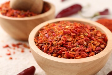 Chili pepper flakes and pods on light textured table, closeup. Space for text