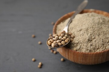 Aromatic spice. Ground pepper in bowl and peppercorns on grey wooden table, closeup. Space for text