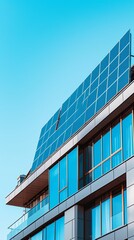 Fototapeta premium Modern building with sleek, blue solar panels installed on its flat rooftop, set against a clear sky