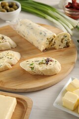 Tasty butter with olives, green onion and bread on wooden table