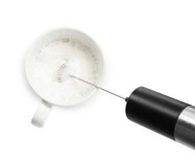 Whisking milk in cup with mini mixer (frother wand) isolated on white, top view