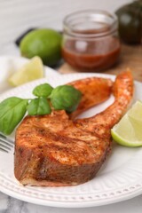 Freshly cooked fish, lime and basil on white marble table, closeup