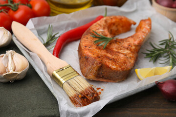 Fresh marinade, fish, brush and other products on wooden table, closeup