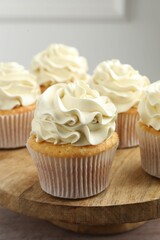 Tasty cupcakes with vanilla cream on pink wooden table, closeup