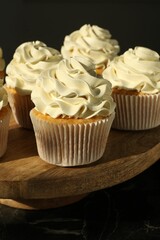Tasty cupcakes with vanilla cream on black table, closeup