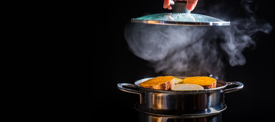 Steamed sweet potatoes in boiling pot steams up as a chef opens the lid of a pot.
