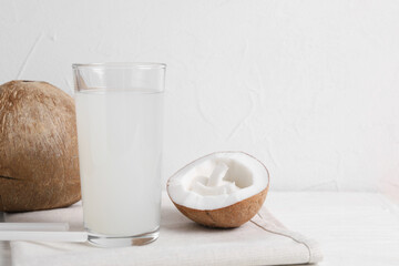 Glass of coconut water and nuts on white table. Space for text