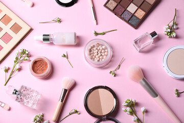 Flat lay composition with different makeup products and beautiful spring flowers on pink background