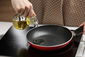 Vegetable fats. Woman pouring cooking oil into frying pan on stove, closeup