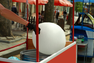 Man making cotton candy with machine outdoors, closeup