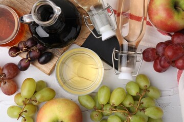 Different types of vinegar and fresh fruits on white table, flat lay