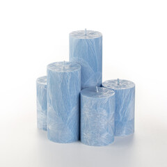 Natural blue palm wax pillar candles of varying heights; featuring unique ice pattern texture grouped on white background. Handmade accessories for refreshing interior decor