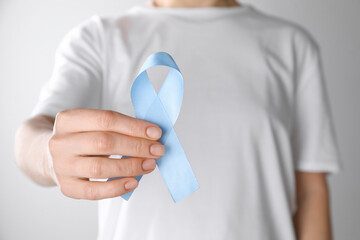 International Psoriasis Day. Woman with light blue ribbon as symbol of support on white background,...