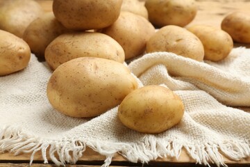 Raw fresh potatoes and napkin on wooden table