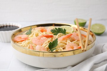 Tasty spaghetti with shrimps and parsley in bowl on white tiled table, closeup