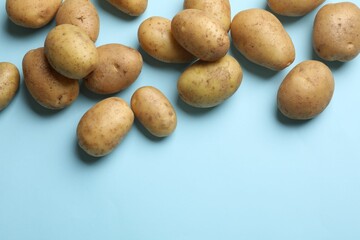 Fototapeta na wymiar Many fresh potatoes on light blue background, flat lay. Space for text