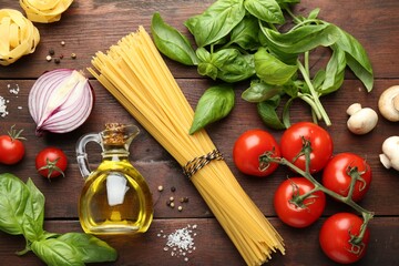 Different types of pasta, spices and products on wooden table, flat lay