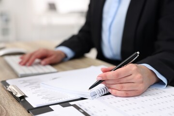 Secretary doing paperwork at table in office, closeup