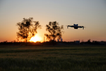Dron w powietrzu nad polami, drone w tle zachód słońca.
