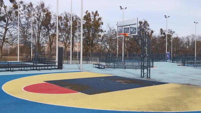 A basketball net under a cloudy sky. The back board has been busted and is now covered with a large piece of wood.