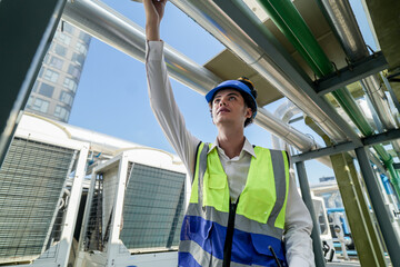 Industrial engineer adjusting pipeline valve with radio communication on construction site. Engineer on urban construction site using radio to coordinate with team on a sunny industrial rooftop.